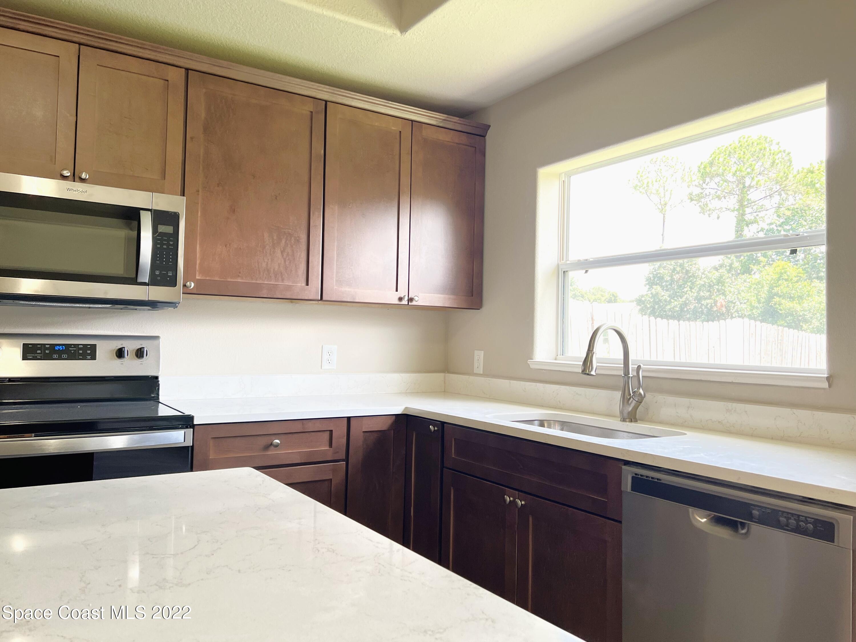 449 Alison Street Titusville, FL 32780 - Photo 9 of 18 a kitchen with a sink a window and appliances