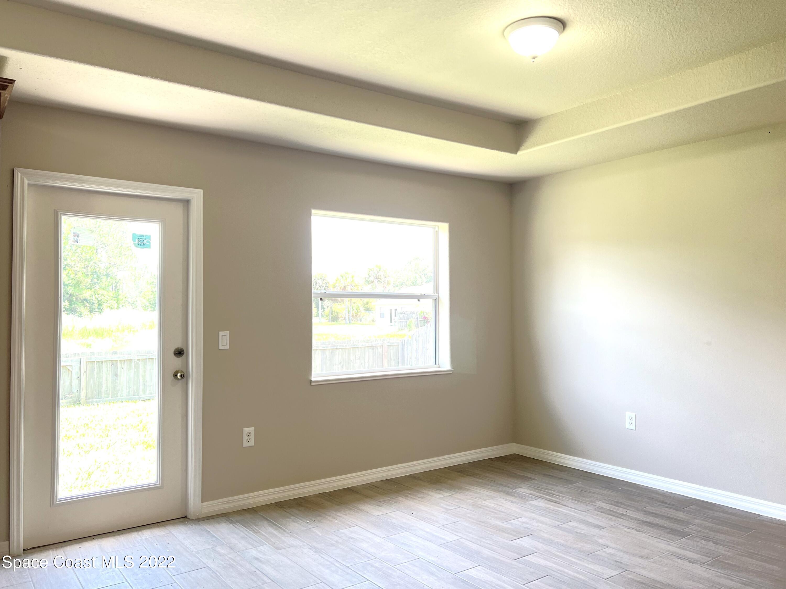 449 Alison Street Titusville, FL 32780 - Photo 10 of 18 a view of an empty room with wooden floor and a window