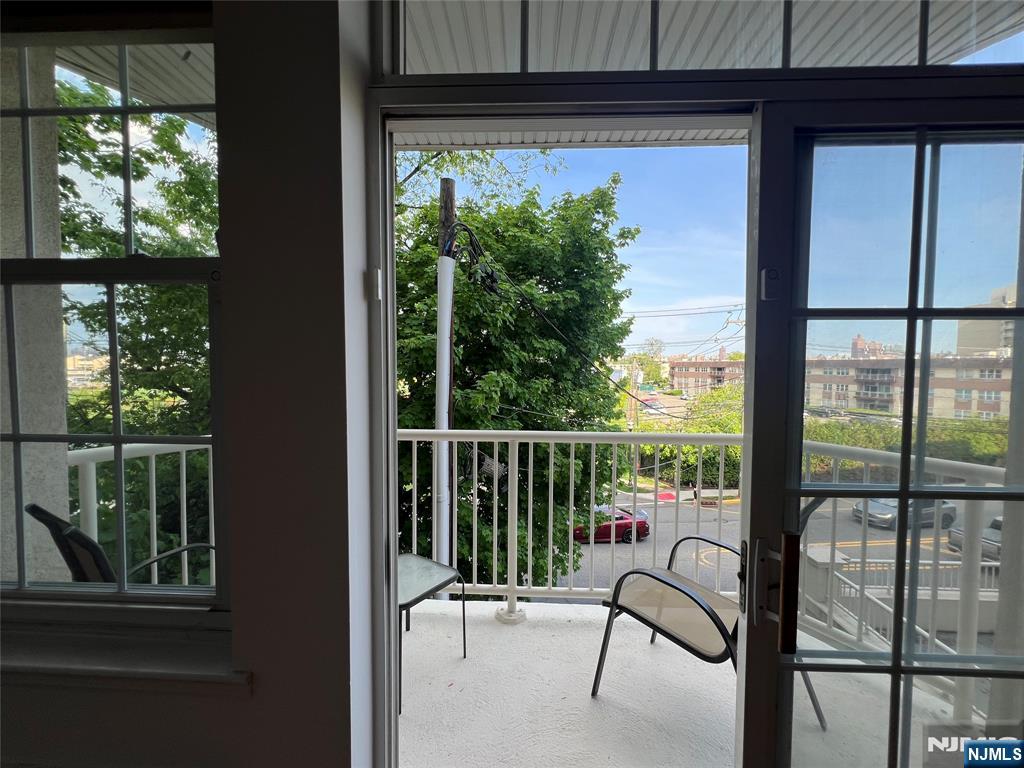 1100 River Road, Unit 206 Edgewater, NJ 07020 - Photo 6 of 13 a view of a balcony with chairs and floor to ceiling window