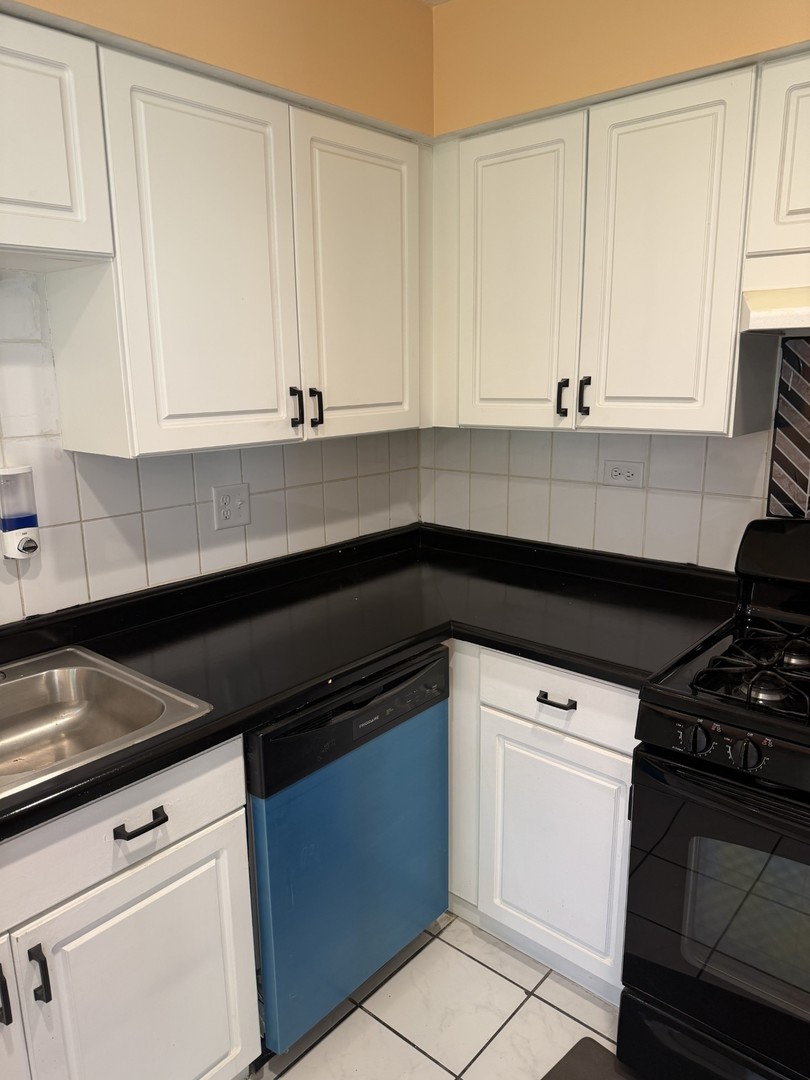 606 Bridgeport Place Wheeling, IL 60090 - Photo 2 of 25 a kitchen with granite countertop white cabinets and black appliances