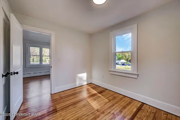 a view of an empty room with window and wooden floor