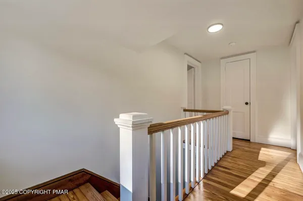 a view of a hallway with wooden floor and staircase