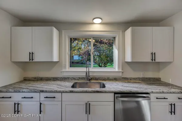 a kitchen with granite countertop a sink window and cabinets