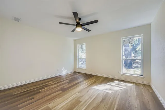 a view of empty room with wooden floor and fan