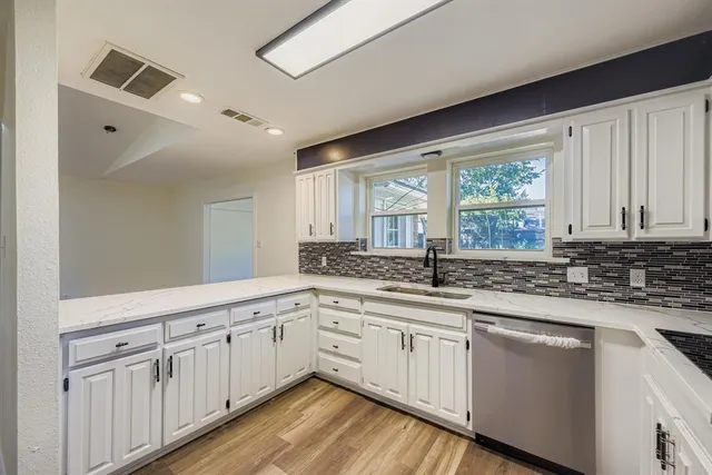 a kitchen with granite countertop white cabinets white appliances and a large window