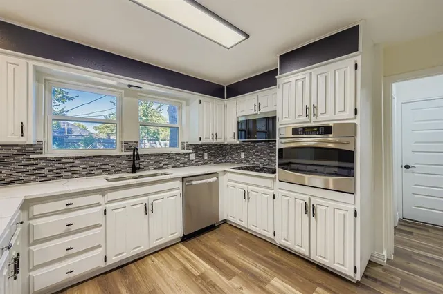 a kitchen with stainless steel appliances granite countertop a stove a sink and white cabinets