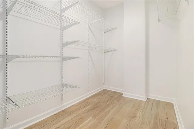 a view of an empty walk in closet with wooden floor