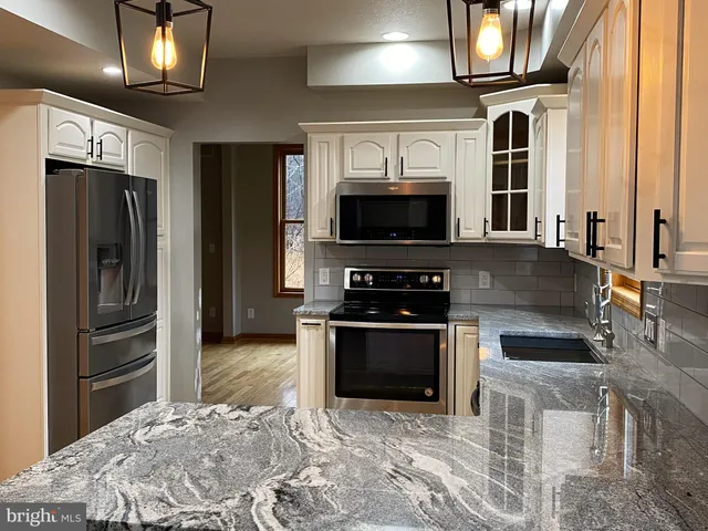 a kitchen with stainless steel appliances granite countertop a stove refrigerator and microwave