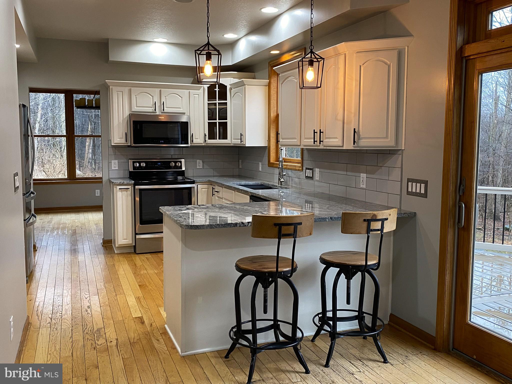 10915 Rachael Avenue Midlothian, MD 21543 - Photo 4 of 52 a kitchen with stainless steel appliances granite countertop a stove top oven a sink dishwasher a dining table and chairs with wooden floor