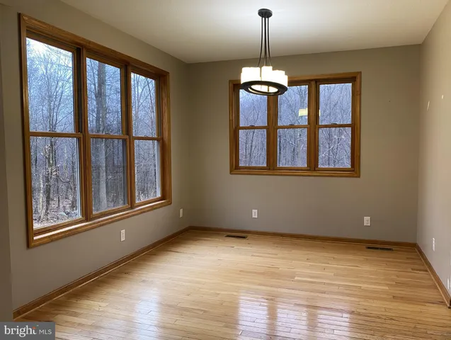 a view of an empty room with a window and wooden floor