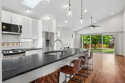 a kitchen with stainless steel appliances granite countertop a sink a stove and a wooden floors