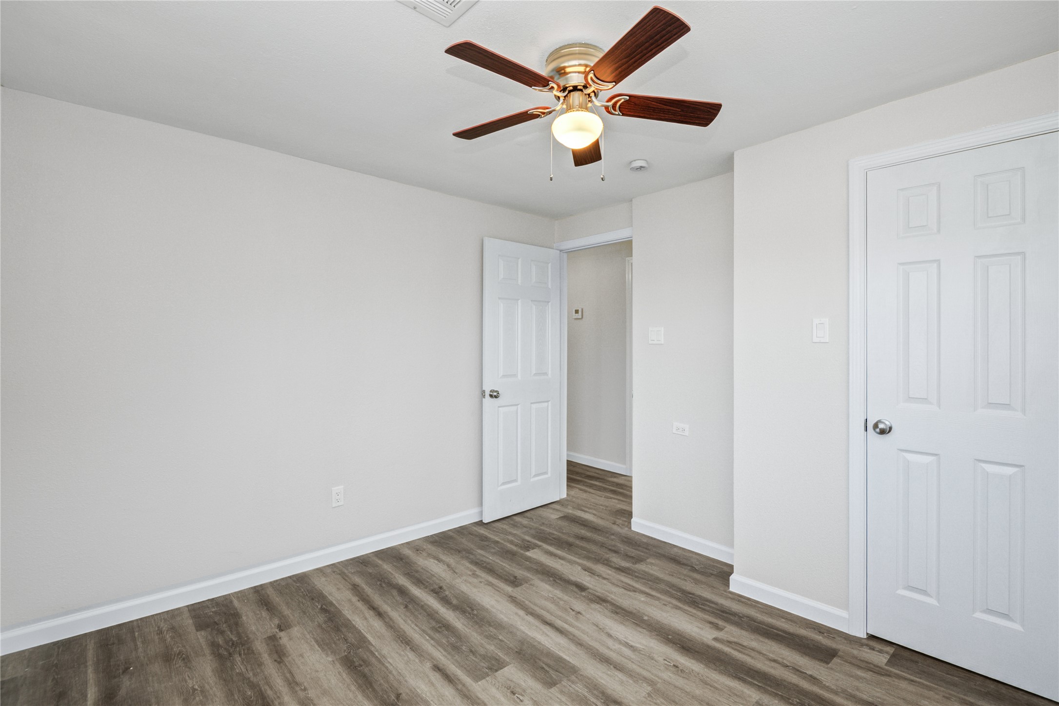207 East Bernard Street Clute, TX 77531 - Photo 19 of 25 an empty room with wooden floor and a ceiling fan