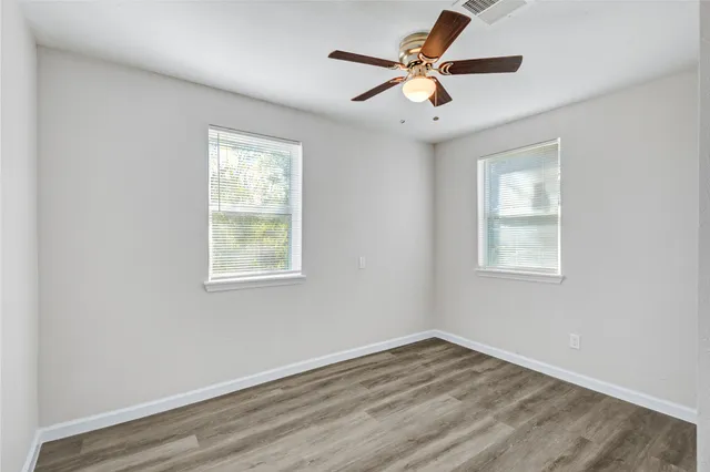 a view of empty room with wooden floor and fan