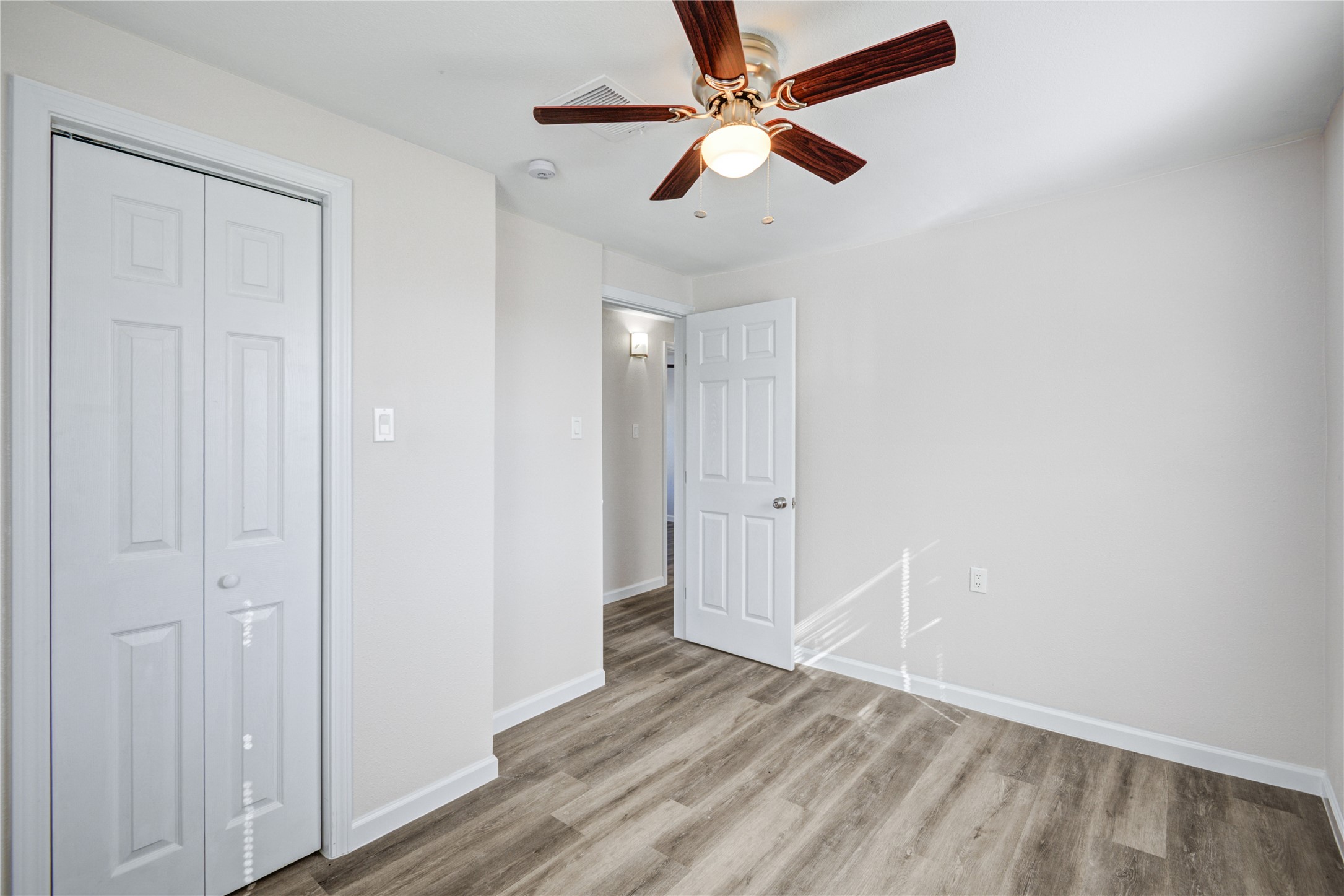 207 East Bernard Street Clute, TX 77531 - Photo 21 of 25 an empty room with wooden floor fan and windows