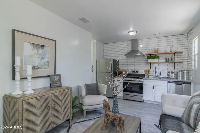 a living room with furniture kitchen view and a wooden floor