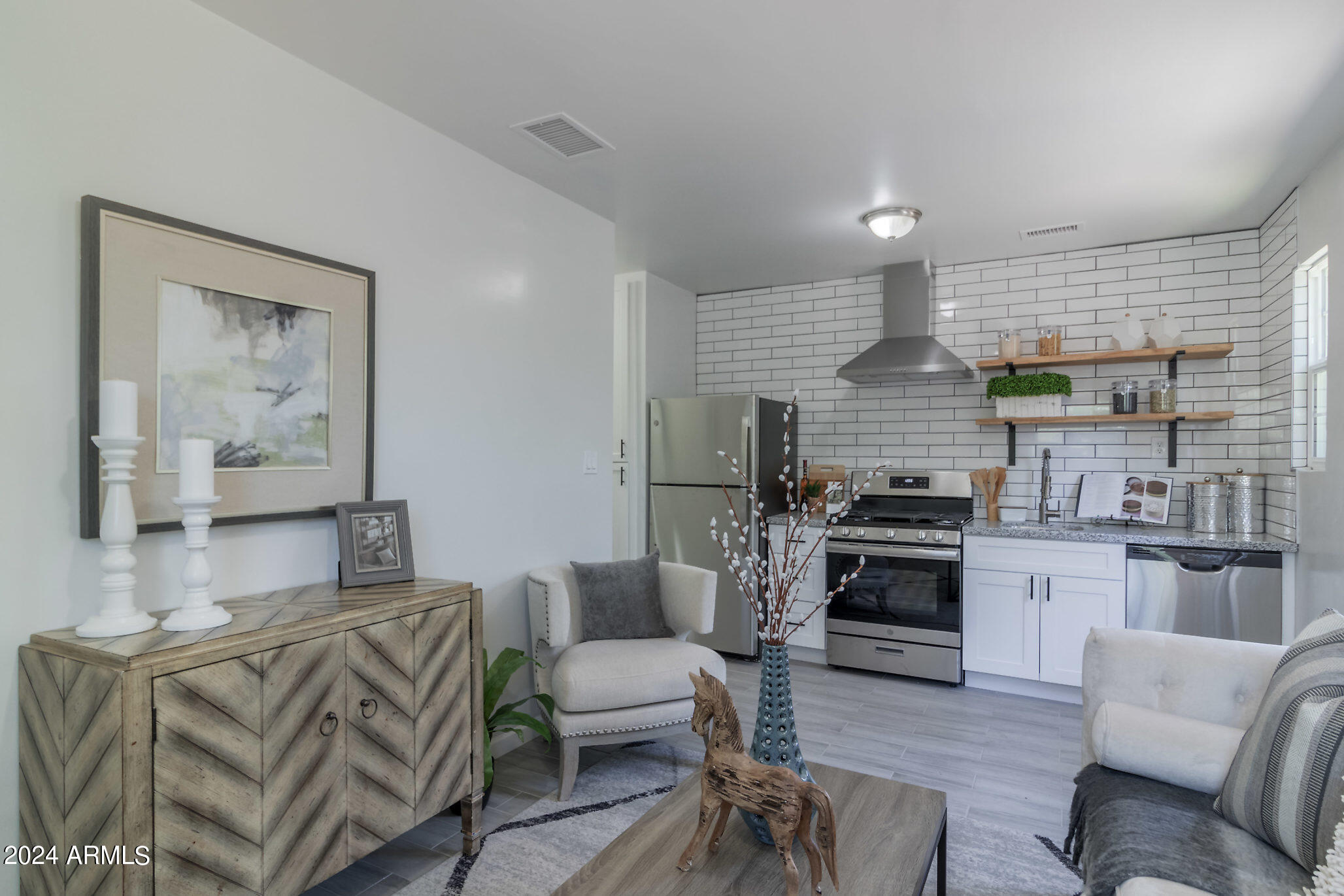 a living room with furniture kitchen view and a wooden floor