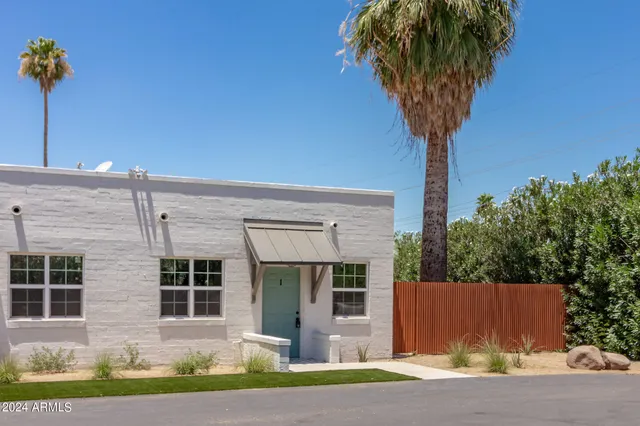 a front view of a house with a yard and potted plants