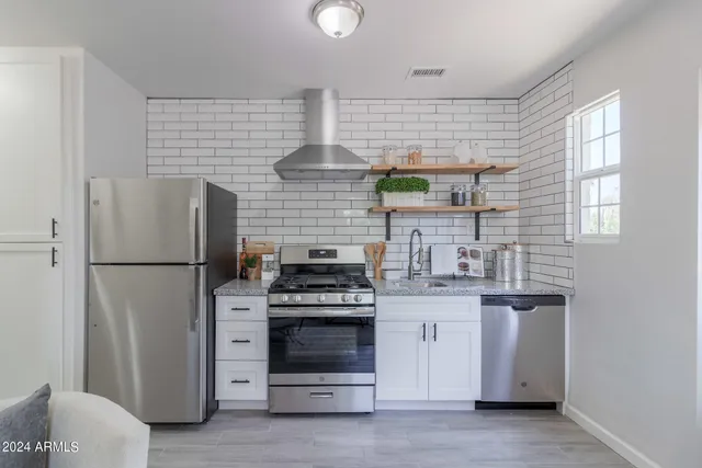 a kitchen with stainless steel appliances a stove a refrigerator and a window