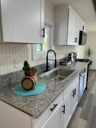 a kitchen with granite countertop a sink a stove and cabinets