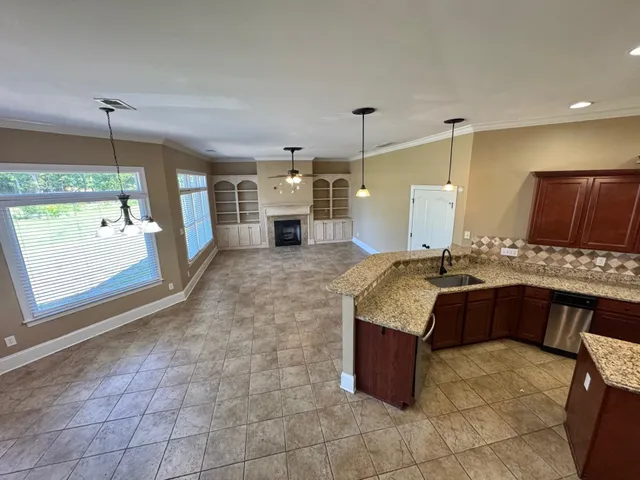 a large kitchen with kitchen island granite countertop a stove a sink a counter space and cabinets