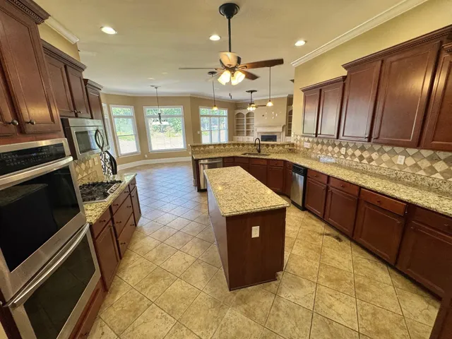 a large kitchen with a stove center island cabinets and stainless steel appliances