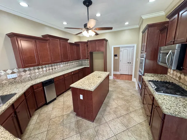 a kitchen with stainless steel appliances granite countertop a stove a sink dishwasher and a refrigerator
