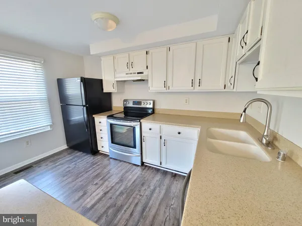 a kitchen with stainless steel appliances granite countertop a refrigerator sink and white cabinets