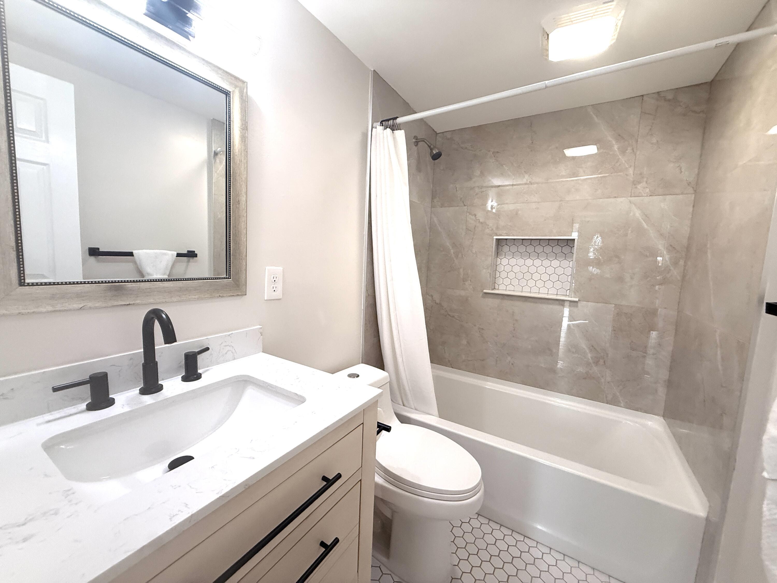 1093 Highview Road Lantana, FL 33462 - Photo 31 of 34 a bathroom with a bathtub shower sink vanity mirror and toilet
