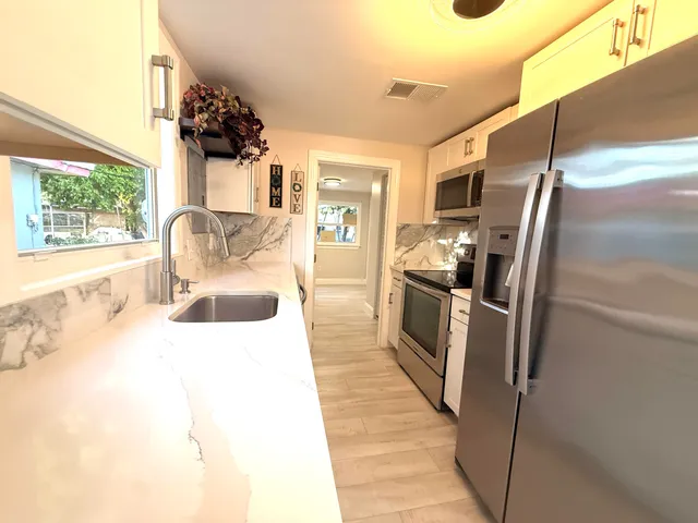 a kitchen with stainless steel appliances granite countertop a refrigerator and a sink