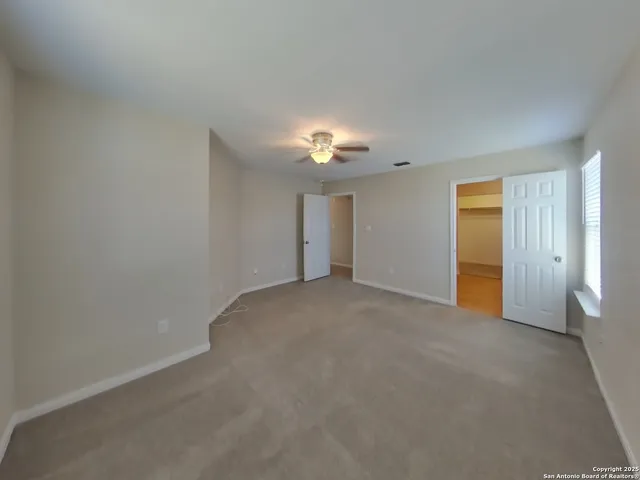 a view of an empty room with a chandelier fan