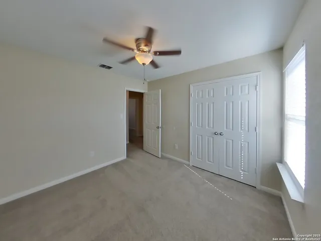 an empty room with a window and a fan