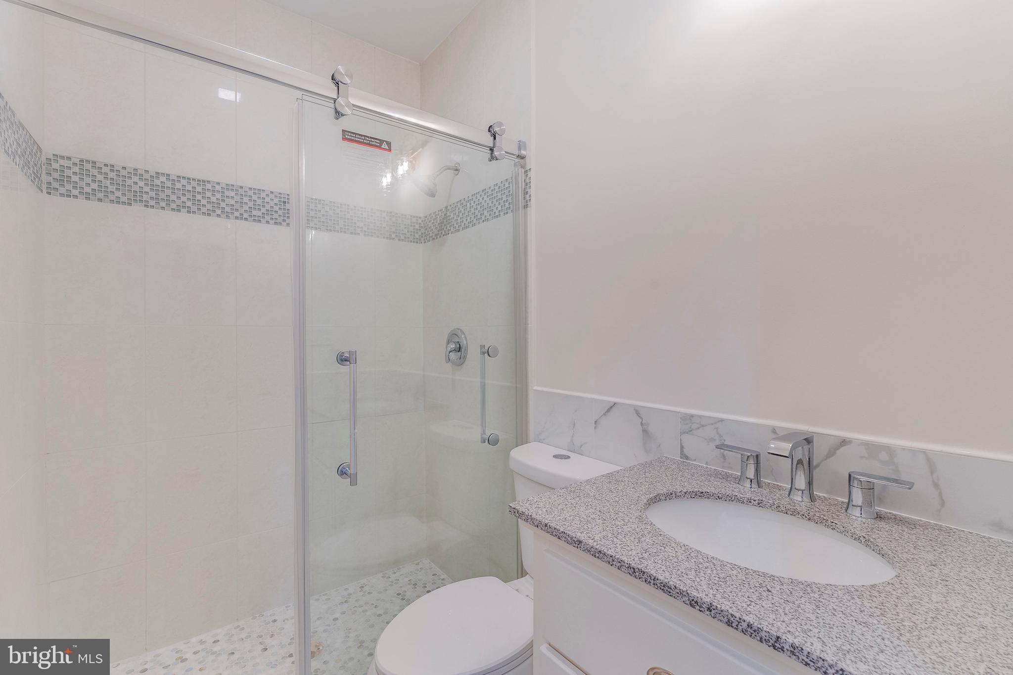 15001 Peach Orchard Road Silver Spring, MD 20905 - Photo 35 of 63 a bathroom with a granite countertop sink toilet a mirror and shower