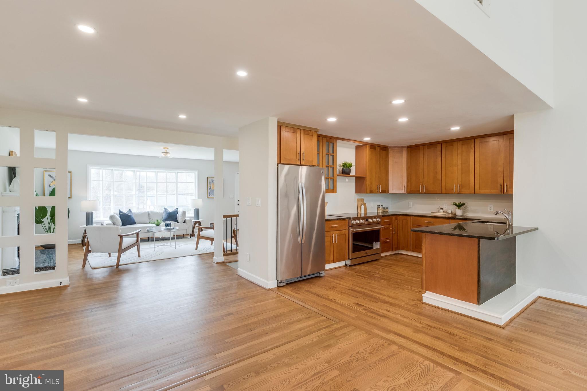 15001 Peach Orchard Road Silver Spring, MD 20905 - Photo 38 of 63 a open kitchen with stainless steel appliances granite countertop a stove top oven a refrigerator a dining table and chairs with wooden floor