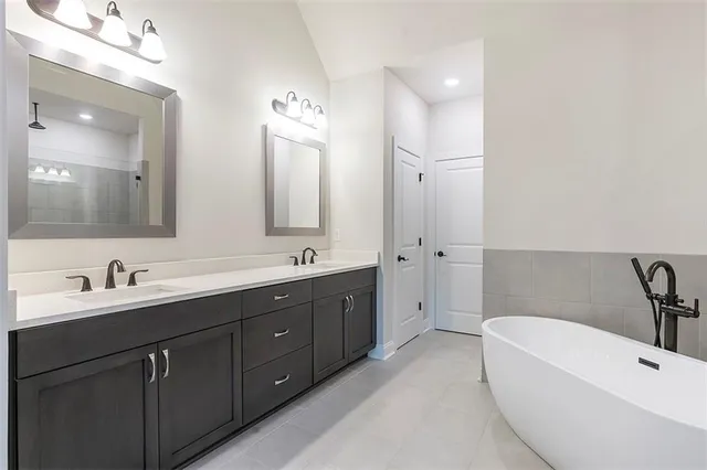 a bathroom with a double vanity sink mirror and bathtub