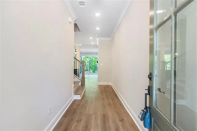 a view of a hallway with wooden floor and a bathroom