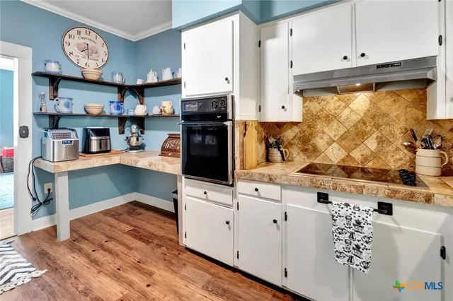 a kitchen with stainless steel appliances granite countertop a stove a sink and a refrigerator with white cabinets