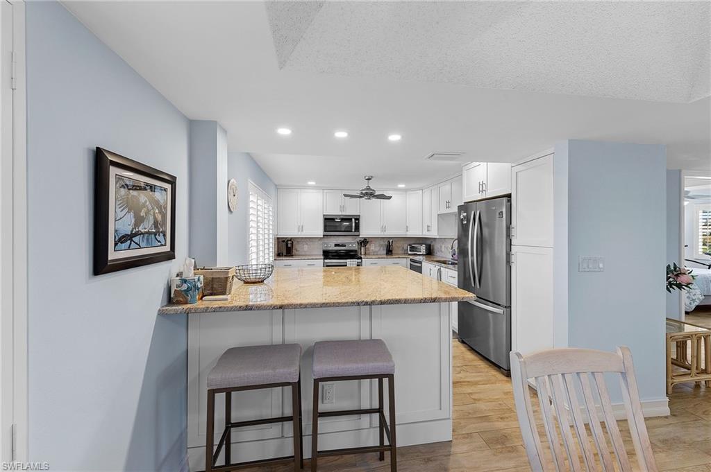 105 Penny Lane, Unit 5 Naples, FL 34112 - Photo 9 of 50 a kitchen with stainless steel appliances a dining table chairs and refrigerator