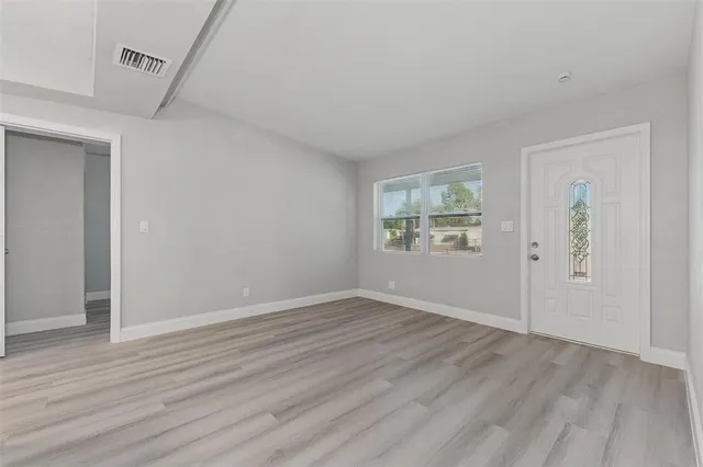 an empty room with wooden floor and windows