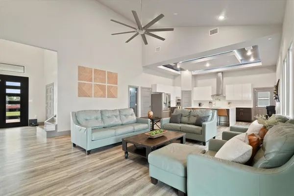a living room with furniture kitchen view and a wooden floor