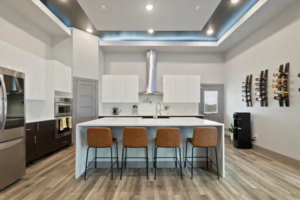 a kitchen with stainless steel appliances a dining table chairs and wooden floor