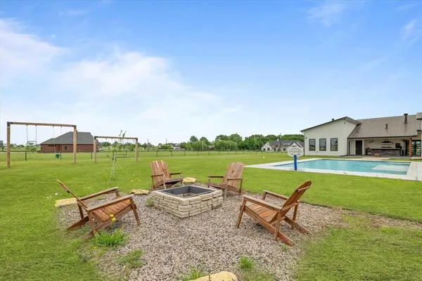 a view of a swimming pool and lounge chairs in back yard of the house