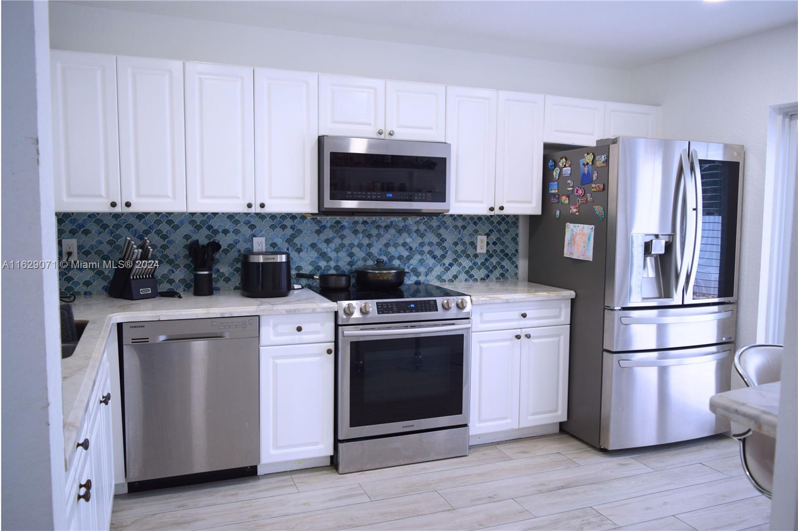 a kitchen with cabinets stainless steel appliances and wooden floor
