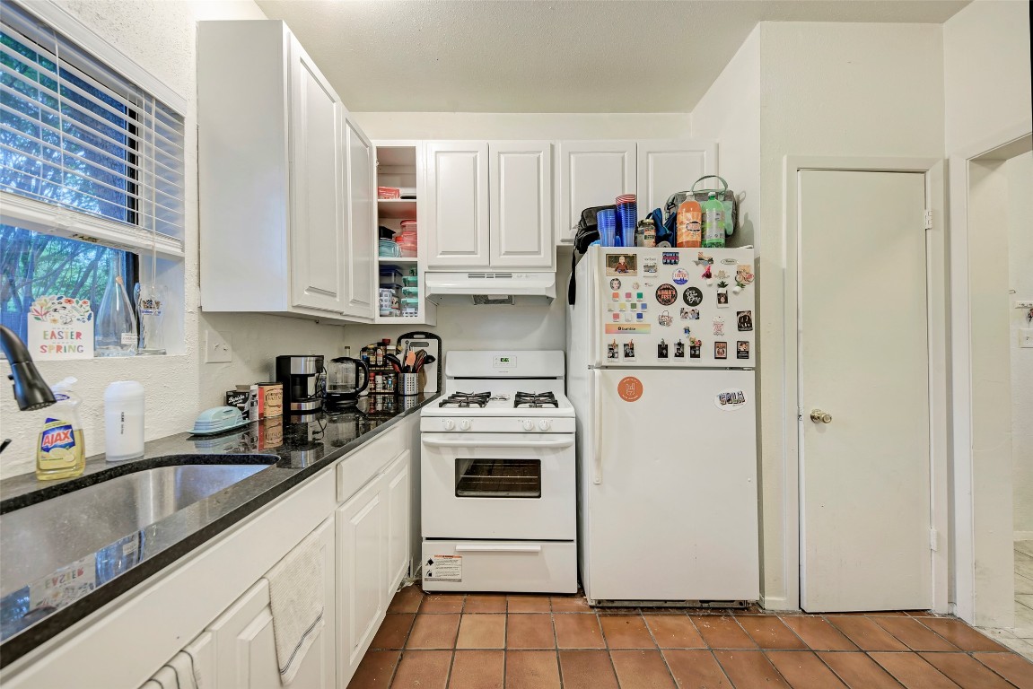 3102 Cedar Street, Unit A Austin, TX 78705 - Photo 6 of 23 a kitchen with stainless steel appliances granite countertop a refrigerator sink and white cabinets