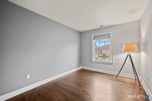 a view of an empty room with a window and wooden floor
