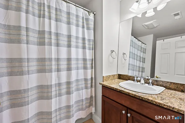 a bathroom with a granite countertop sink a mirror a vanity and shower