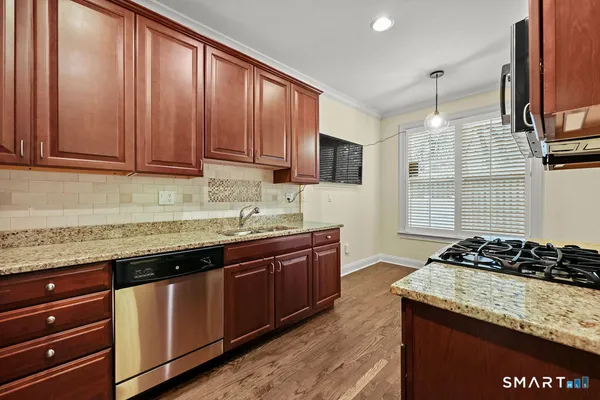 a kitchen with granite countertop stainless steel appliances a stove sink and cabinets