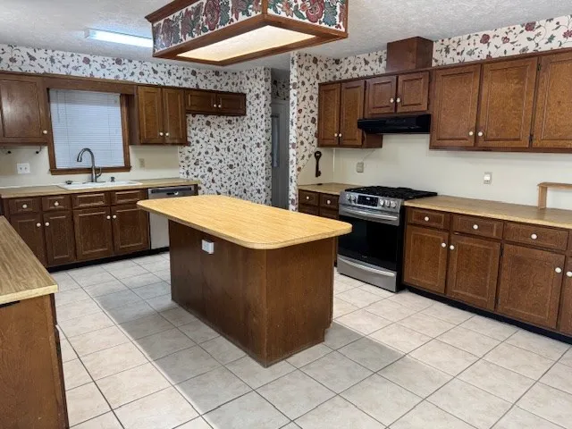 a kitchen with stainless steel appliances granite countertop a stove a sink and a microwave