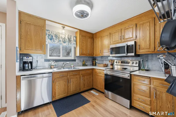 a kitchen with stainless steel appliances granite countertop a stove a sink dishwasher and a microwave oven with wooden floor