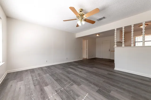 an empty room with wooden floor and windows