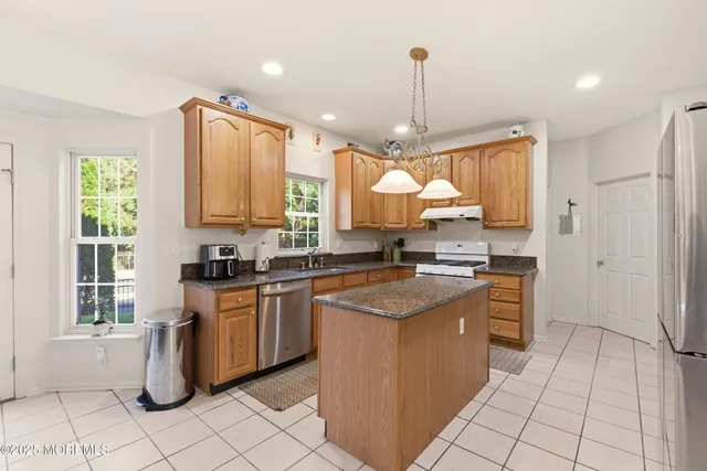 a kitchen with stainless steel appliances granite countertop a stove top oven a sink a dining table and chairs